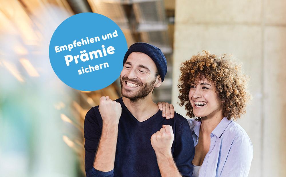 Eine Mann ballt die Faust und freut sich, eine Frau legt die Hand auf seine Schulter und lacht ebenfalls